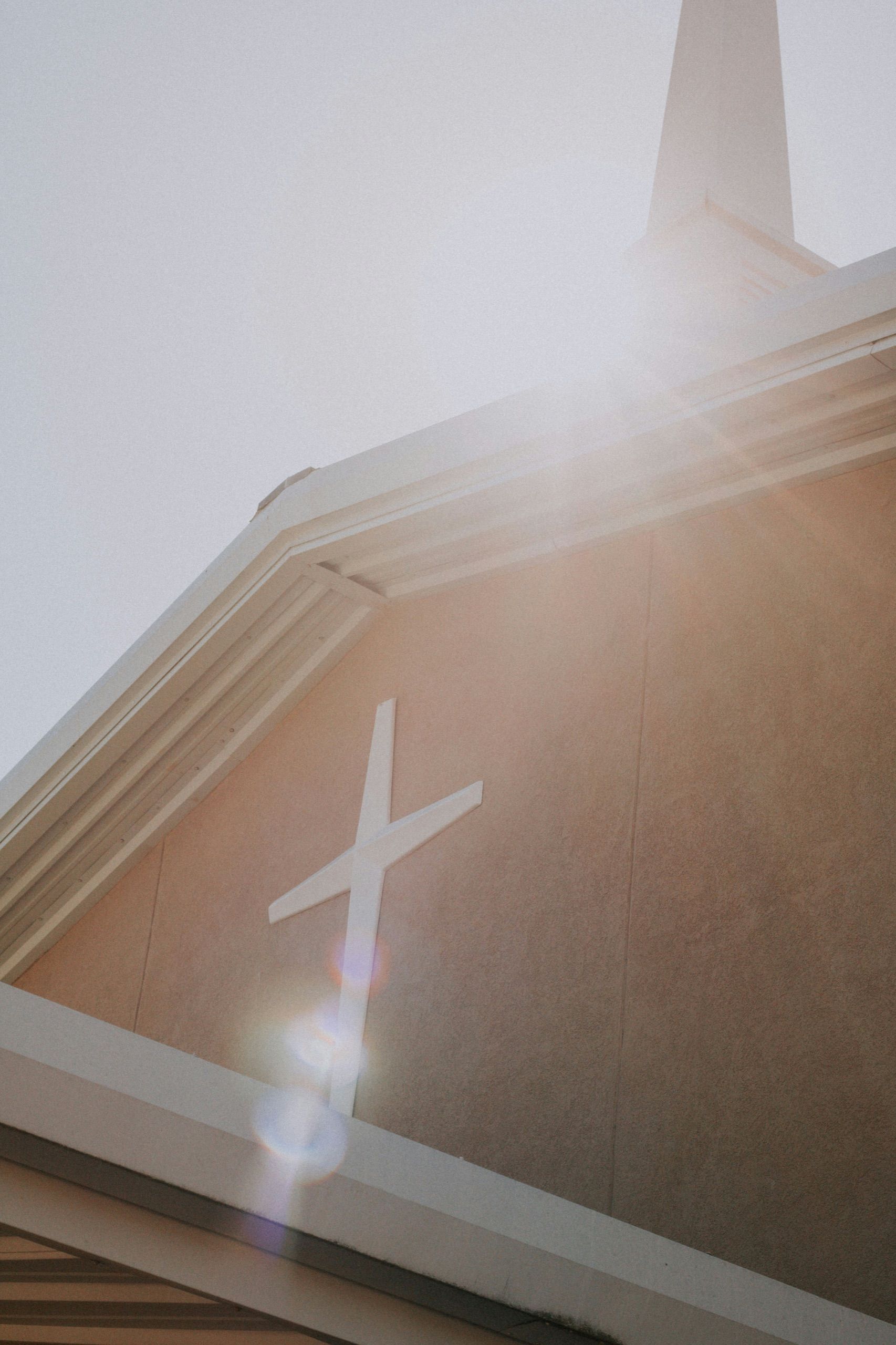 Kirchenfassade mit weißem Kreuz und Turm im Sonnenlicht
