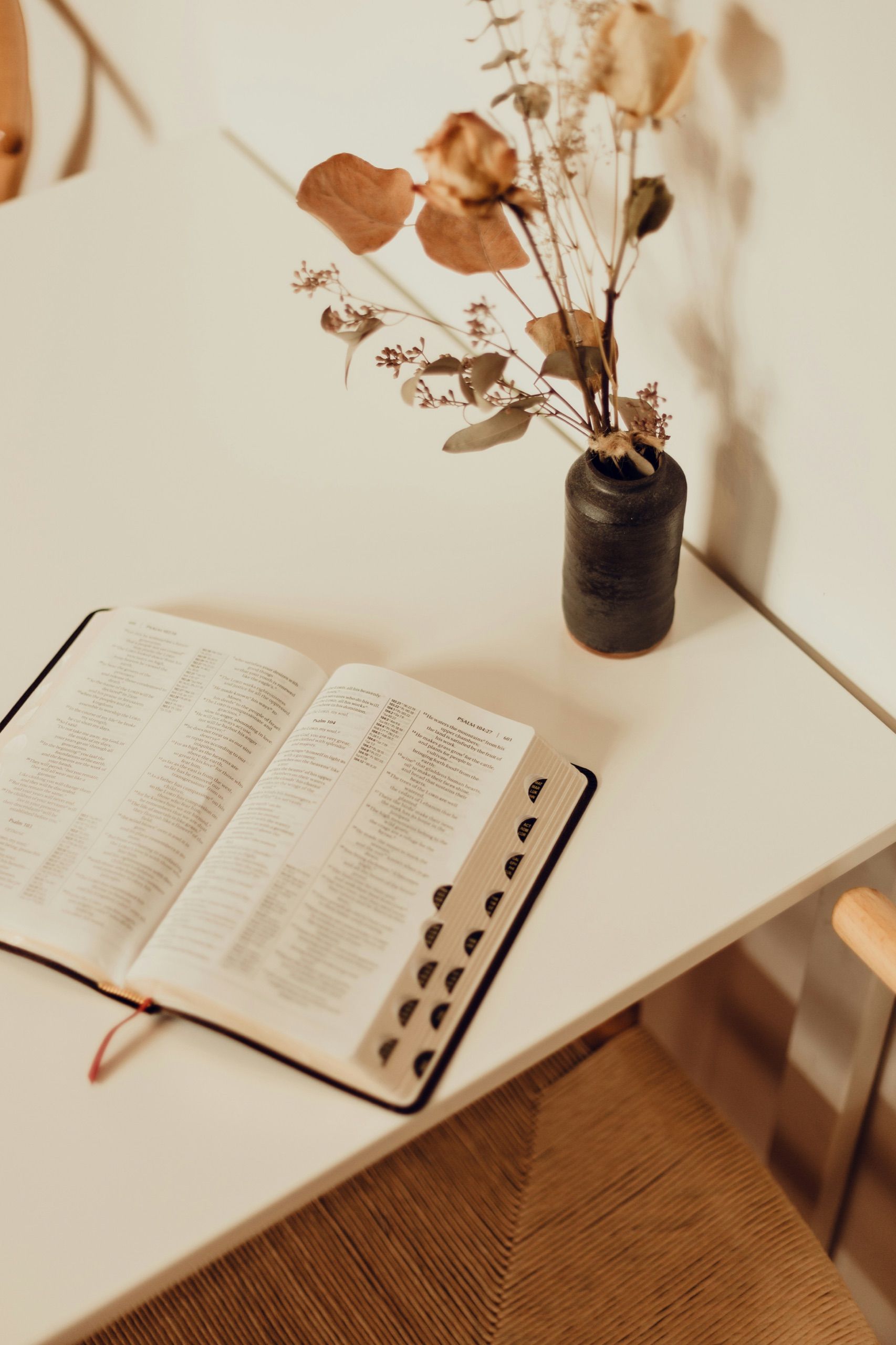 Bibel und getrocknete Blumen auf einem hellen Tisch